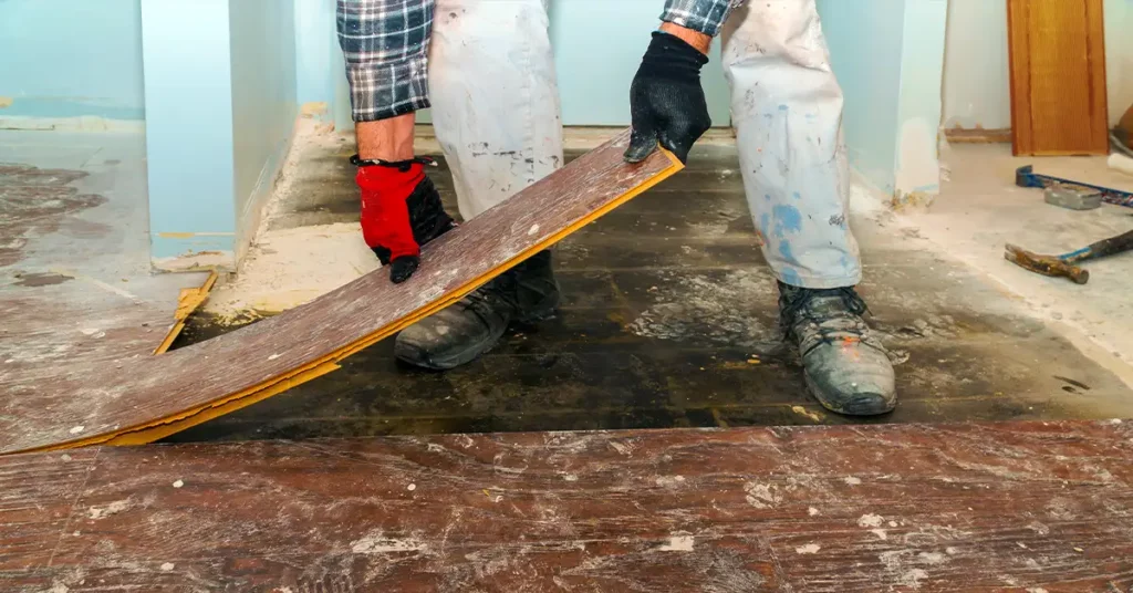 Manual worker disassembling old laminated parquet floor
